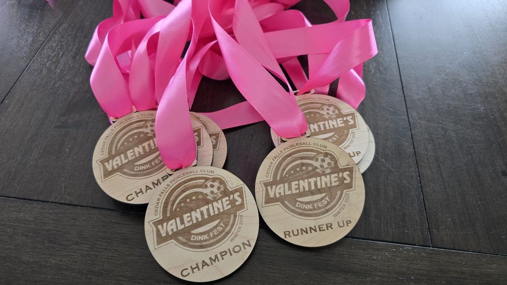 Round wooden medals with bright pink ribbons for the Cedar Falls Pickleball Club Valentine's Dink Fest.